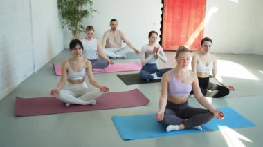 Yoga farkındalığı meditasyonu. Yoga sağlık farkındalığı meditasyonu için stüdyoda egzersiz yapan bir grup sporcu. Nilüfer çiçeğinde oturup yoga yapan erkek kadınlar meditasyon yapıyor.