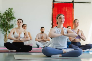 Yoga farkındalığı meditasyonu. Yoga sağlık farkındalığı meditasyonu için stüdyoda egzersiz yapan bir grup sporcu. Nilüfer çiçeğinde oturup yoga yapan erkek kadınlar meditasyon yapıyor.