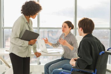 Takım çalışması beyin fırtınası. Çeşitli çok ırklı meslektaşlar birlikte çalışan engelli insanlar için sandalyede oturuyor. Yaratıcı ofiste oturup iş konuşan bir grup insan. Genç profesyonel takım