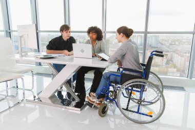 Takım çalışması beyin fırtınası. Çeşitli çok ırklı iş arkadaşları olan kadın engelliler için birlikte çalışıyor. Yaratıcı ofiste oturup iş konuşan bir grup insan. Genç profesyonel takım