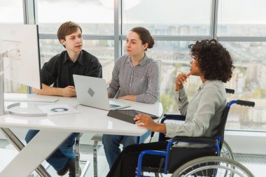 Takım çalışması beyin fırtınası. Çeşitli çok ırklı iş arkadaşları olan kadın engelliler için birlikte çalışıyor. Yaratıcı ofiste oturup iş konuşan bir grup insan. Genç profesyonel takım