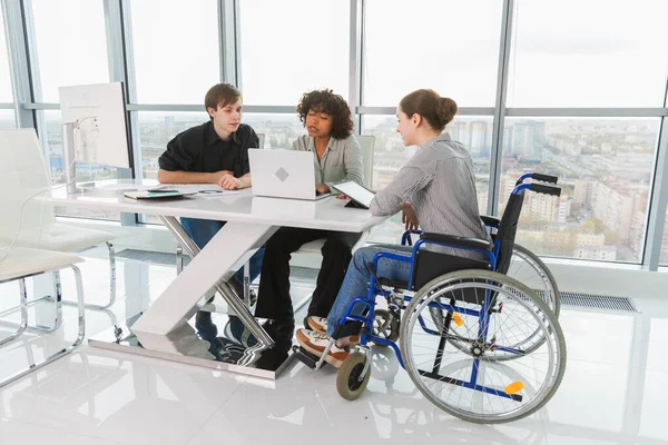 Takım çalışması beyin fırtınası. Çeşitli çok ırklı iş arkadaşları olan kadın engelliler için birlikte çalışıyor. Yaratıcı ofiste oturup iş konuşan bir grup insan. Genç profesyonel takım