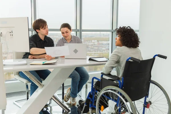 Takım çalışması beyin fırtınası. Çeşitli çok ırklı iş arkadaşları olan kadın engelliler için birlikte çalışıyor. Yaratıcı ofiste oturup iş konuşan bir grup insan. Genç profesyonel takım