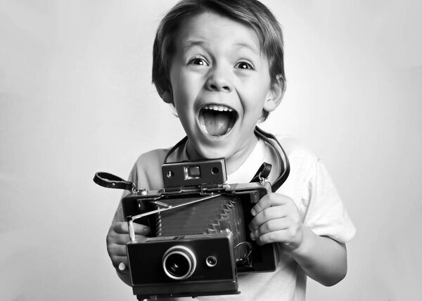 young child holding a instant camera on a white background