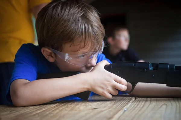 boy aiming rifle at gun range