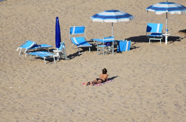 人けのないビーチ パラソルと水浴びをする人 — ストック写真