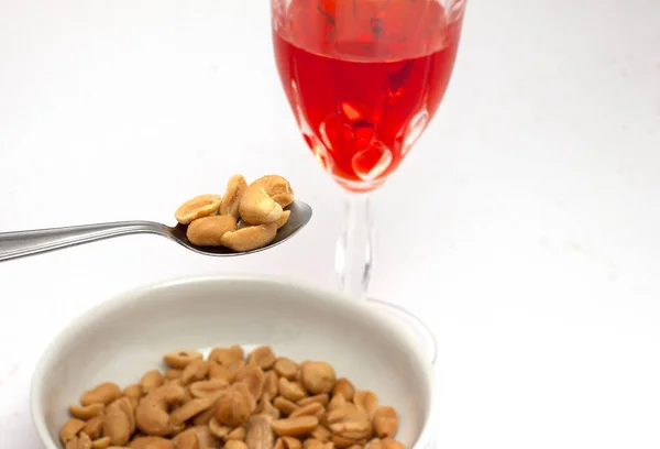 stock image aperitivo con noccioline e bevanda alcolica rossa nel calice