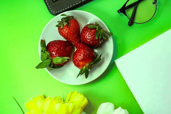 office workspace. Strawberry. artificial flowers, stationery, glasses, keyboard. toned background