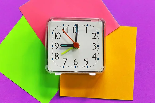 a desk clock on colored stickers. on a toned background.