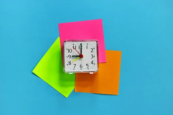 a desk clock on colored stickers. on a toned background.