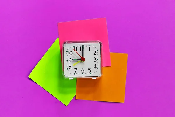 a desk clock on colored stickers. on a toned background.