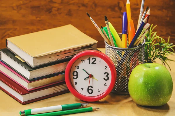 books, clocks, apple, stationery on a wooden table. Concept of education.