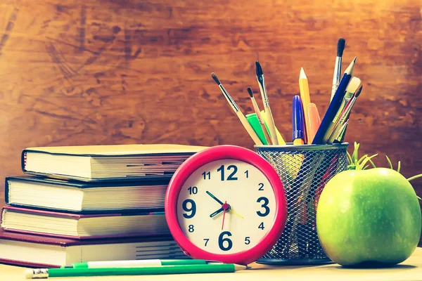 books, clocks, apple, stationery on a wooden table. Concept of education.