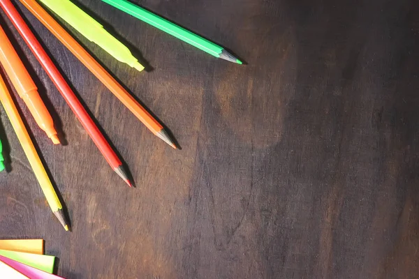 School and office stationery on a background of a dark wooden board.