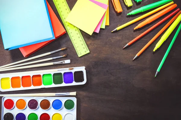 School and office stationery on a background of a dark wooden board.