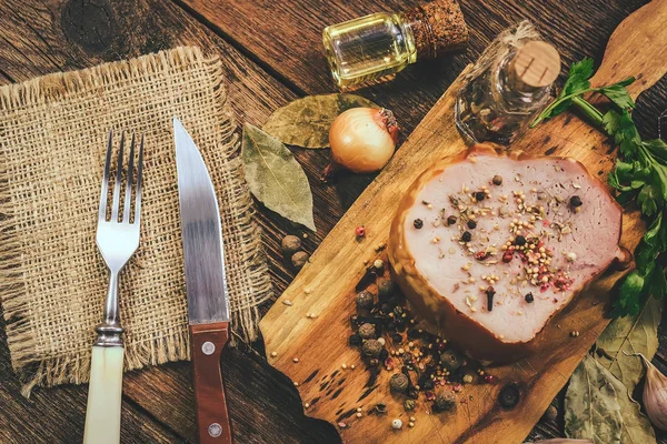 ham with spices and oils on a wooden background