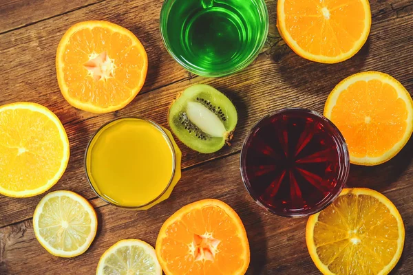 juices of citrus and slices of orange and mandarin on a wooden background.