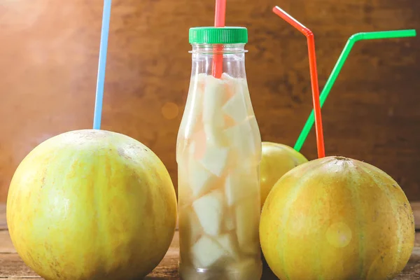Fruit melons and straws for juice. A bottle with slices of melon and juice.
