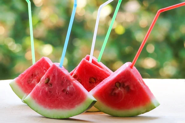 slices of watermelon with straws for juice.