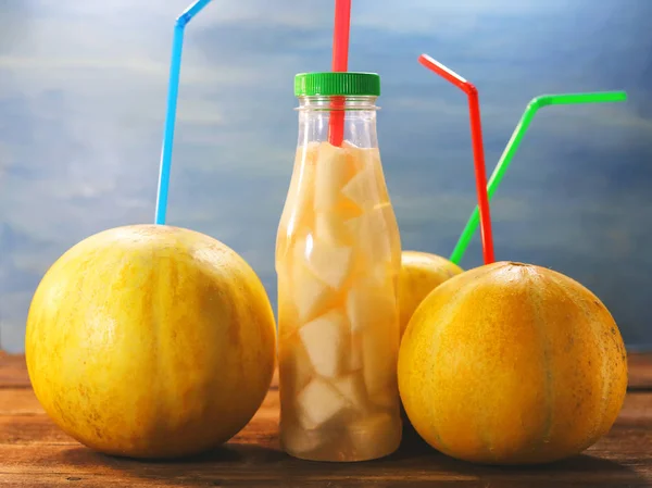 Fruit melons and straws for juice. A bottle with slices of melon and juice.