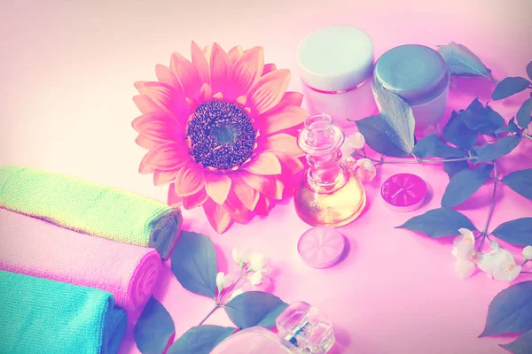 Beauty background with cosmetic products, bottle of perfume, leaves and jasmine blossom on toned  background. spa.  top view, flat lay. desktop, copy space.
