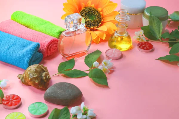 Beauty background with cosmetic products, bottle of perfume, leaves and jasmine blossom on toned  background. spa.  top view, flat lay. desktop, copy space.