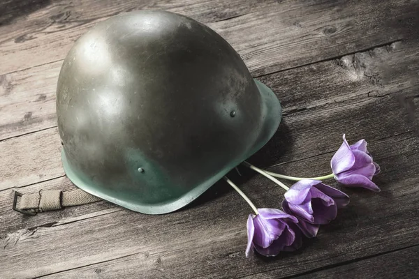 military helmet and flowers on a wooden background. the concept of memory of the heroes of war.