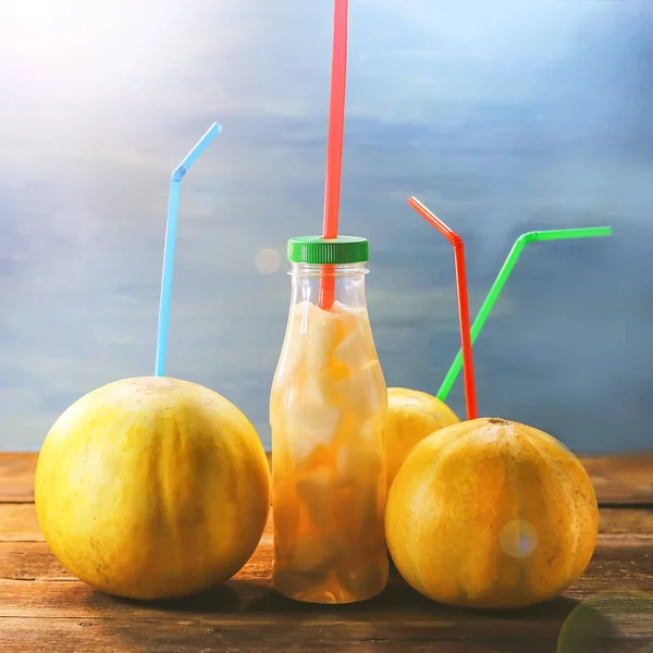 Fruit melons and straws for juice. A bottle with slices of melon and juice.