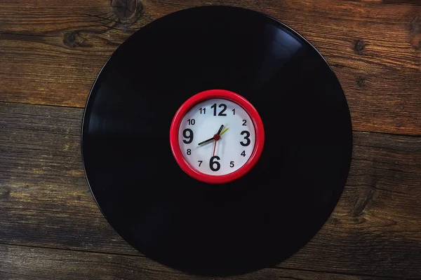 The clock on black vinyl  record. Music concept, retro.