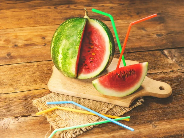 cut watermelon with straws for juice. on a wooden background.
