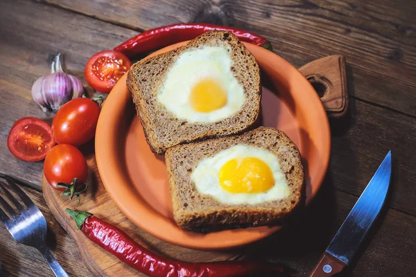 fried bread. fried eggs in a heart-shaped symbol. vegetables. on a wooden board
