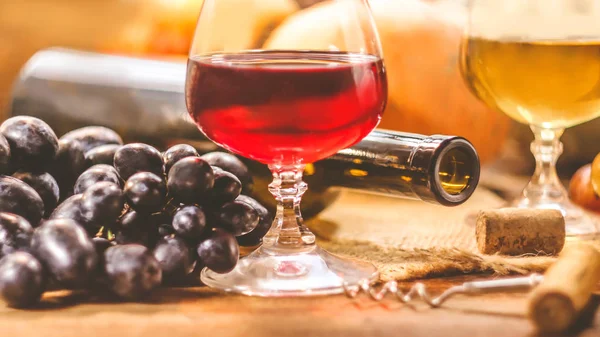 A bottle of wine on a background of glasses and grapes on a wooden table