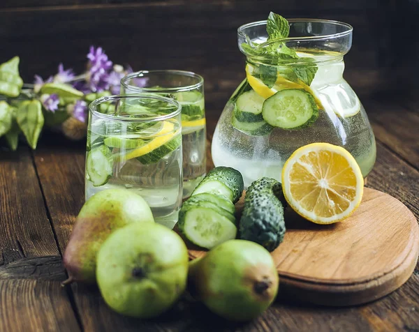 Detox water in a pitcher and glasses with cucumbers. A healthy drink.