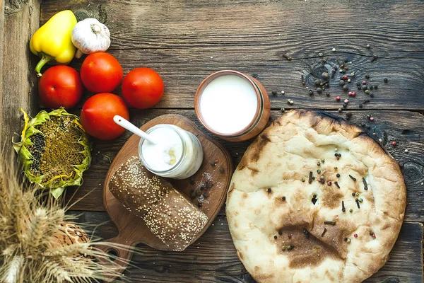 Bread, milk and vegetables on a wooden table. Wooden background.