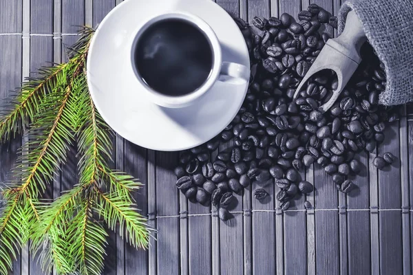A cup of black coffee with New Year and Christmas attributes. Spruce branch.