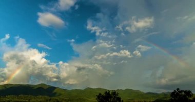 Büyük bulutlar hareket hızlı ve gökkuşağı gökyüzü ve dağlar hızlandırılmış