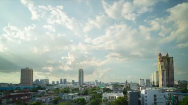 Stratocumulus bulutları bir katman oluşturur ve Tayland 'ın Bangkok kentindeki yerleşim yerlerindeki binaların üzerinden hızla geçer..