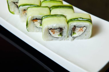 Salatalık karides ve krem peynir portre ile beyaz bir plaka üzerinde rulo..