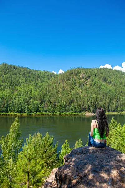 Giovane donna in viaggio seduta sulla cima della scogliera di montagna . — Foto Stock