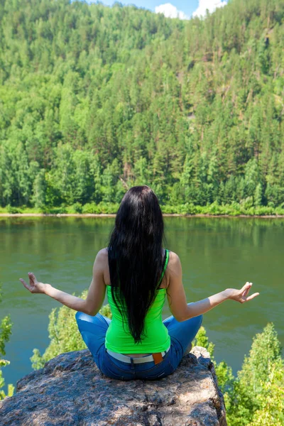 Donna che medita in posizione di loto facendo yoga in cima alla montagna su una roccia . — Foto Stock