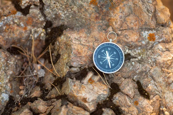 Magnetisch kompas met een zwarte wijzerplaat op een wild steen bedekt met mos. — Stockfoto