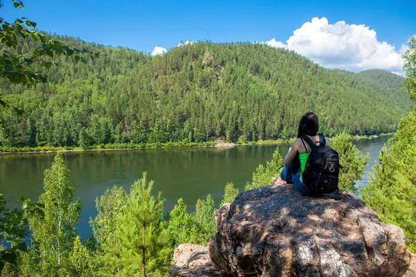 Giovane donna in viaggio seduta sulla cima della scogliera di montagna . — Foto Stock