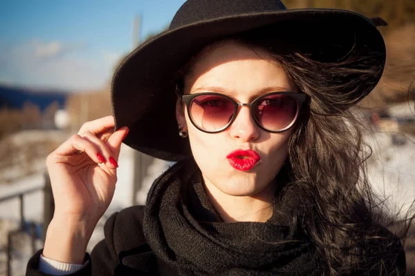 Young woman posing in black coat and black hat. — Stock Photo, Image