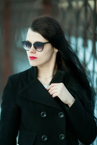 Ung kvinne i svart frakk og svart hatt . – stockfoto