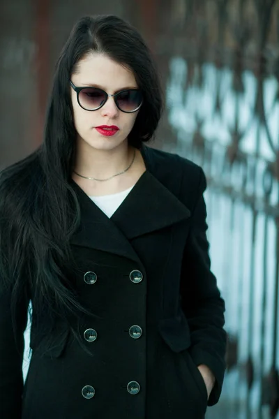 Giovane donna in posa in cappotto nero e cappello nero . — Foto Stock