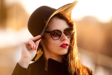 Genç kadın siyah ceket ve siyah şapka poz.