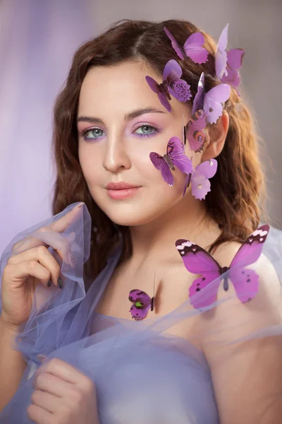 Schöne junge Frau mit künstlichem Schmetterling im lockigen Haar. — Stockfoto