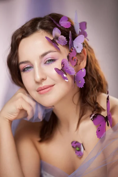 Schöne junge Frau mit künstlichem Schmetterling im lockigen Haar. — Stockfoto