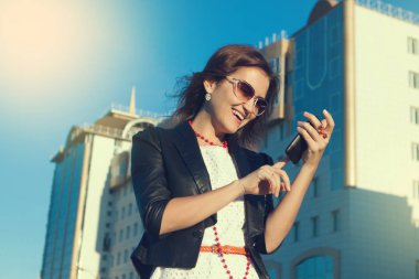 Sanny gün şehirde bir cep telefonu kullanarak çekici iş kadını.