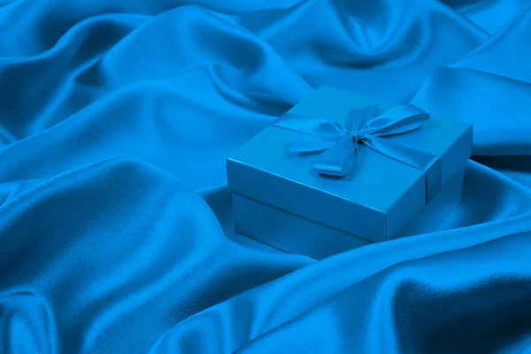 Blaue Geschenkschachtel auf blauer Seide. Grußkarte Bakcground. — Stockfoto